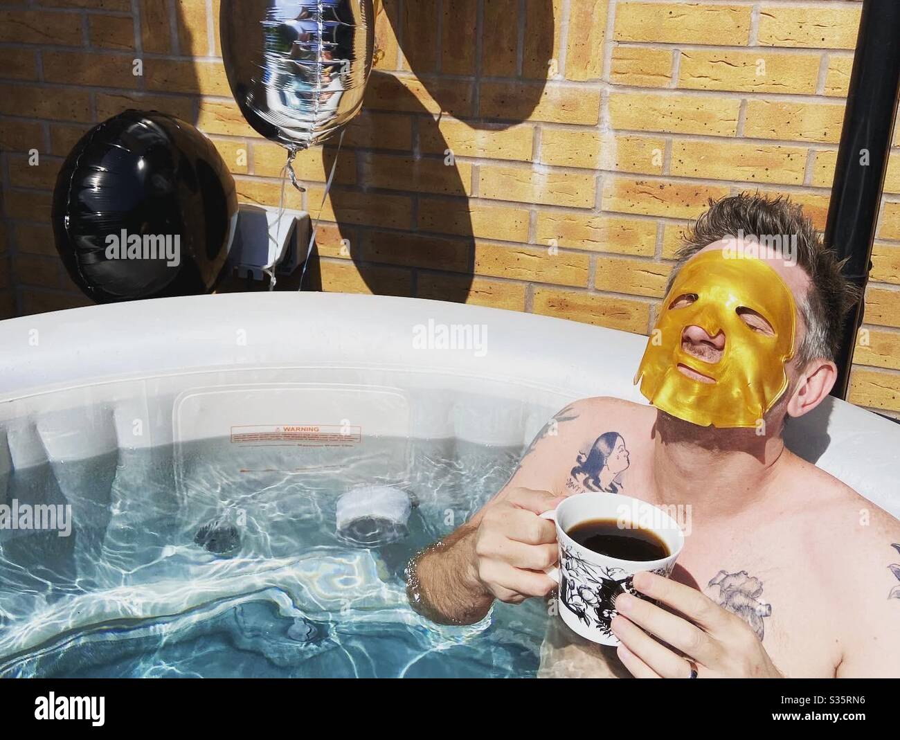 Man with a face mask on in an inflatable hot tub - Smartphone Captured Stock Image