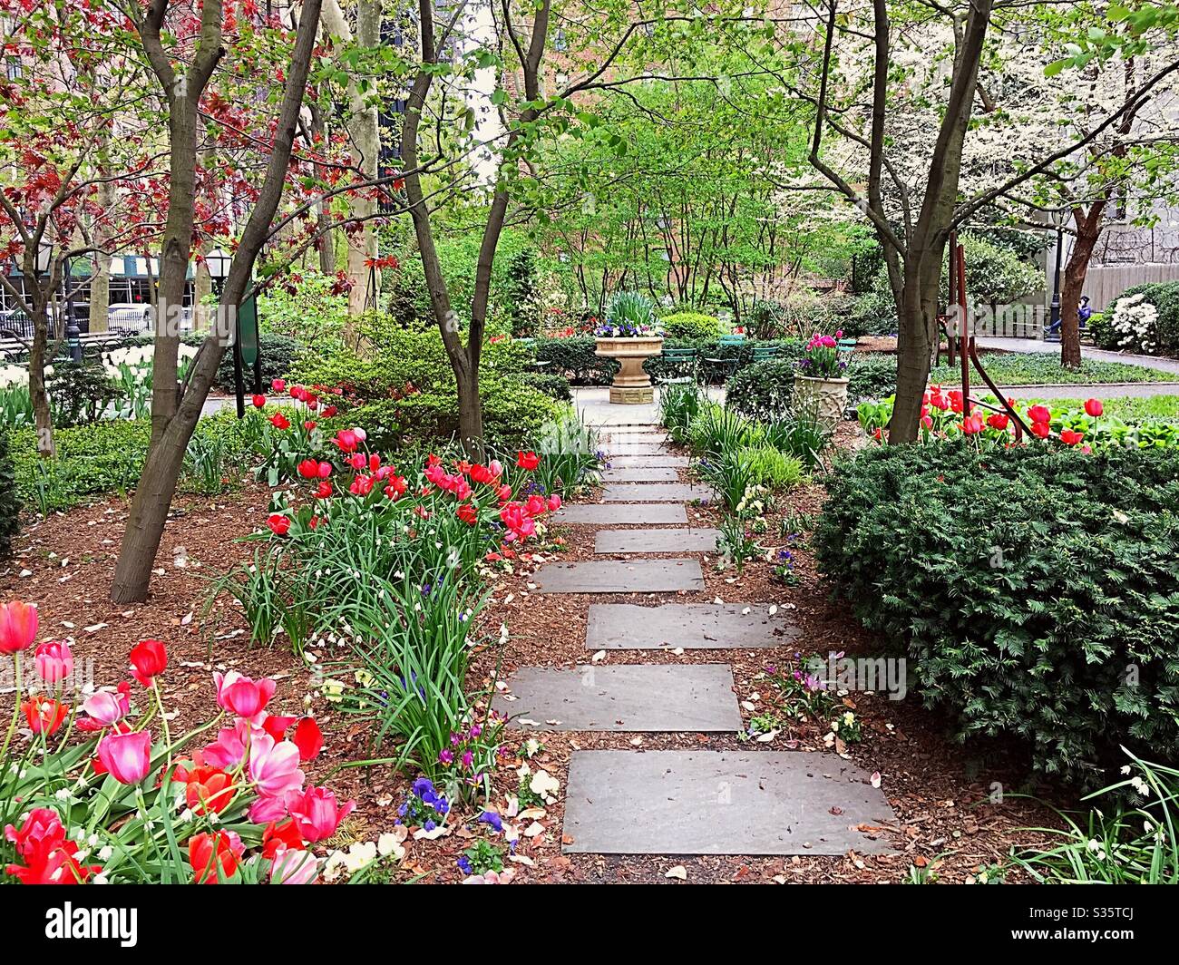 Flagstone steps lead to an ornate stone birdbath in Tudor city greens, NYC, USA - Smartphone Captured Stock Image