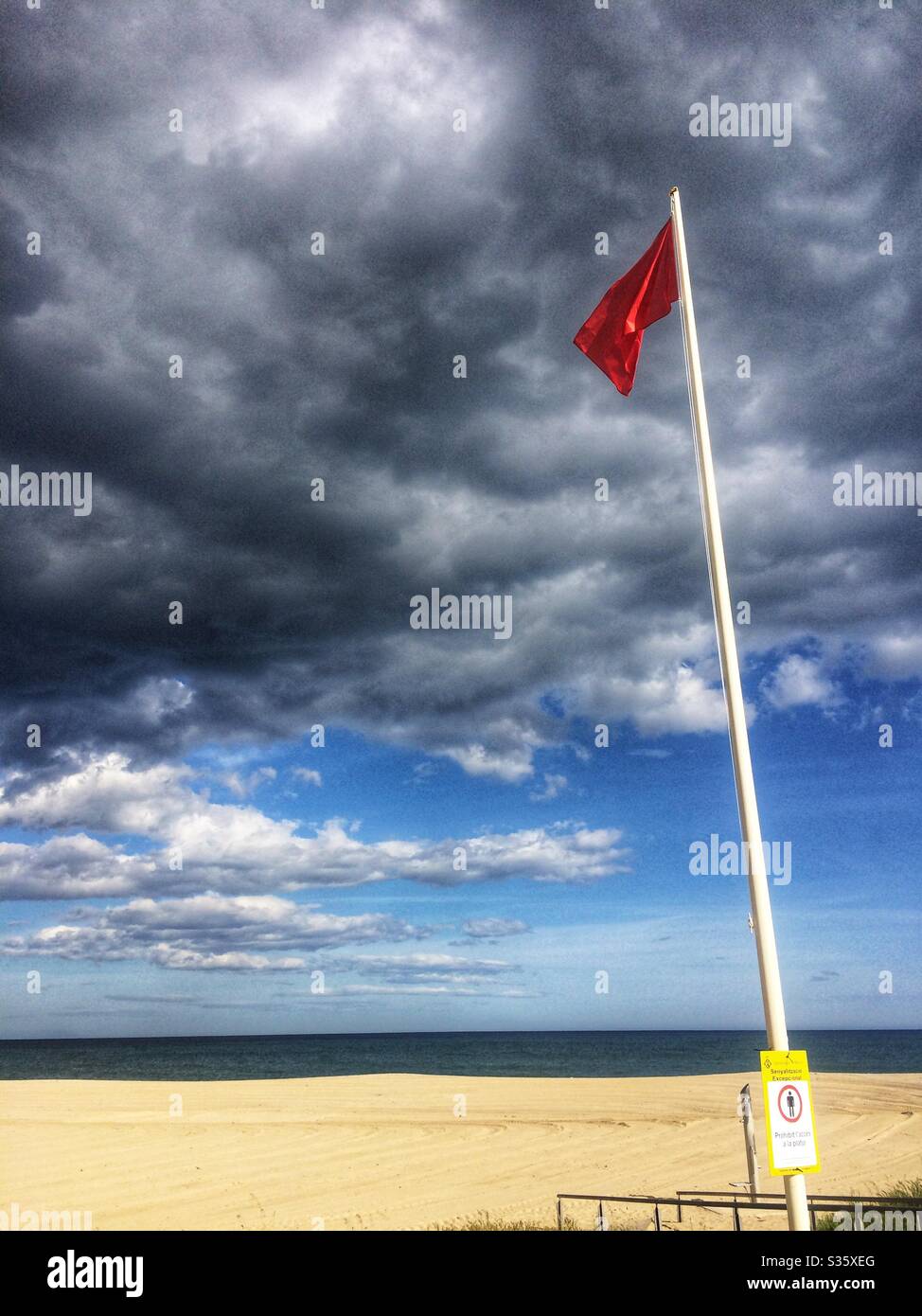 Red flag because covid-19 pandemy confinement quarantine , in a beach of Mataró, Barcelona province, Catalonia, Spain Stock Photo