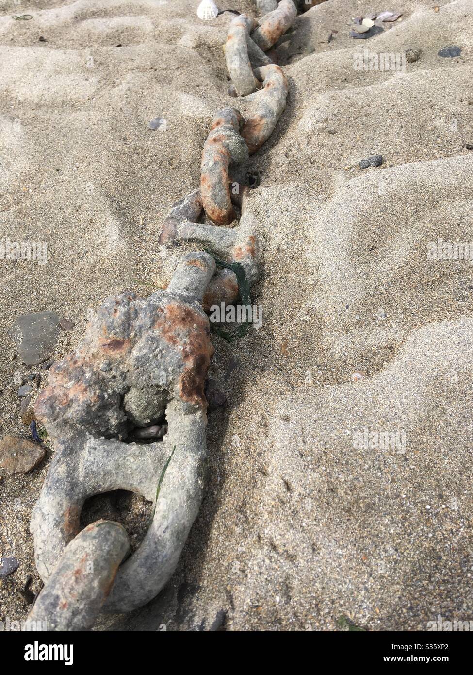 An old iron chain, scrap metal on a sandy beach - Smartphone Captured Stock Image