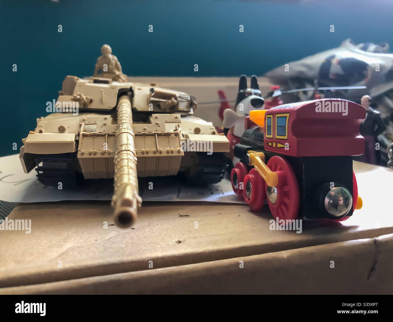 A toy model tank and wooden train on a ledge on a child’s bedroom. - Smartphone Captured Stock Image