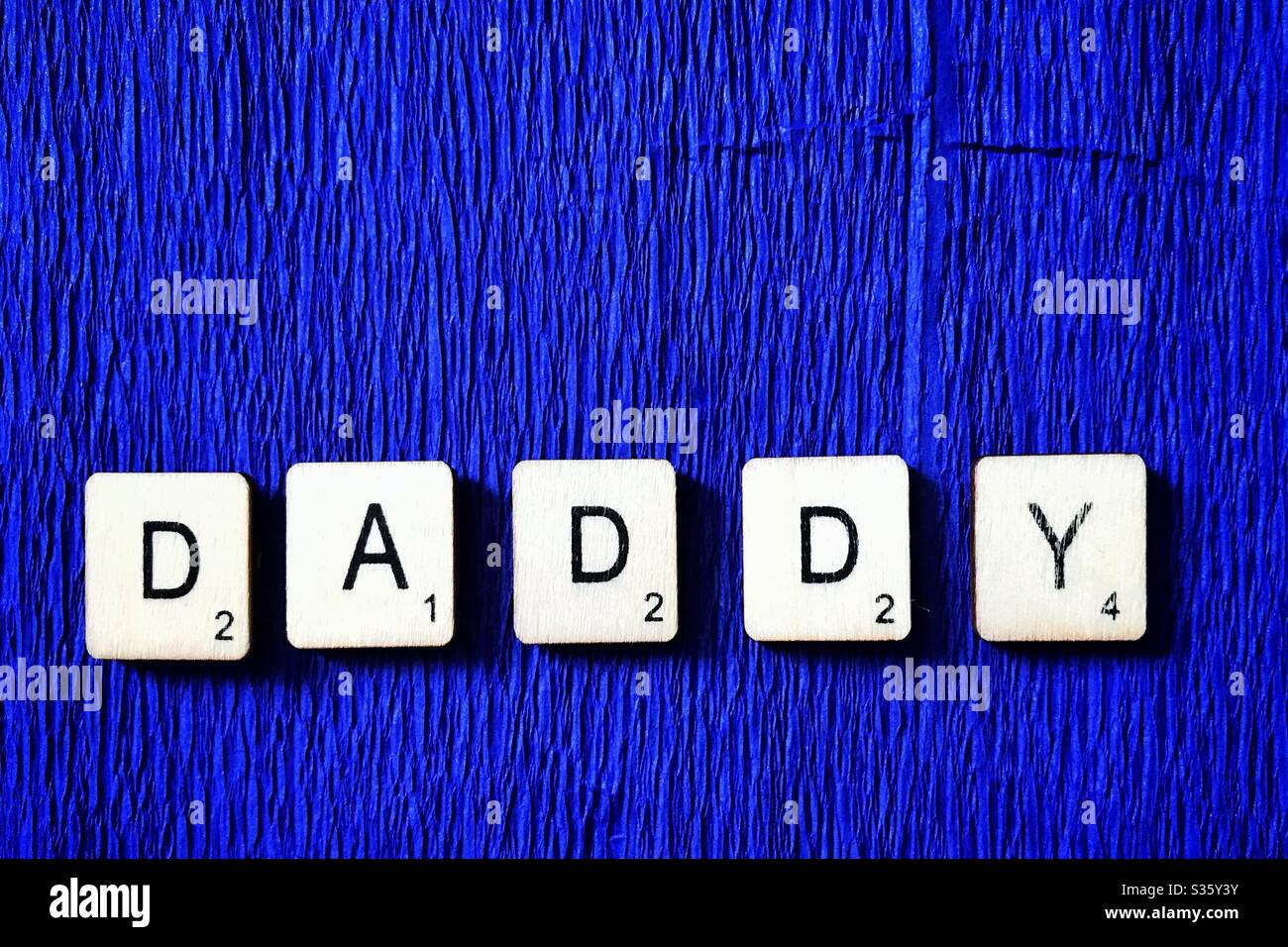 Wooden tiles spelling out Daddy. - Smartphone Captured Stock Image