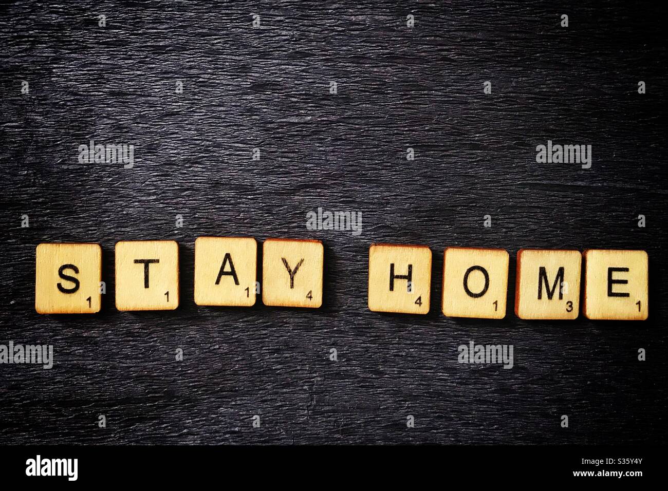 Wooden tiles spell out Stay Home. Stock Photo