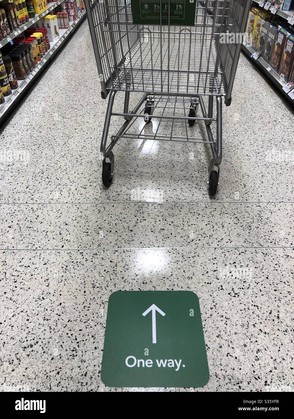 Shopping cart going one way in a supermarket during the coronavirus pandemic - Smartphone Captured Stock Image