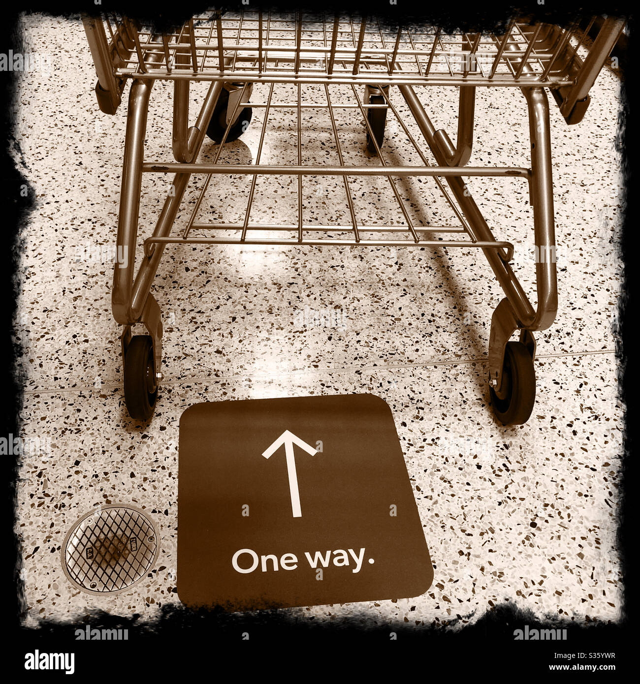Shopping cart and one way sign on the floor in a supermarket during the Coronavirus Pandemic, April 2020 Stock Photo