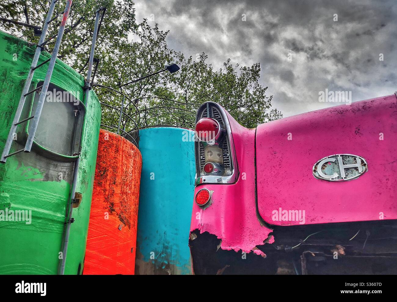 Tail of vintage car painted shocking pink with other colourful junk Stock Photo