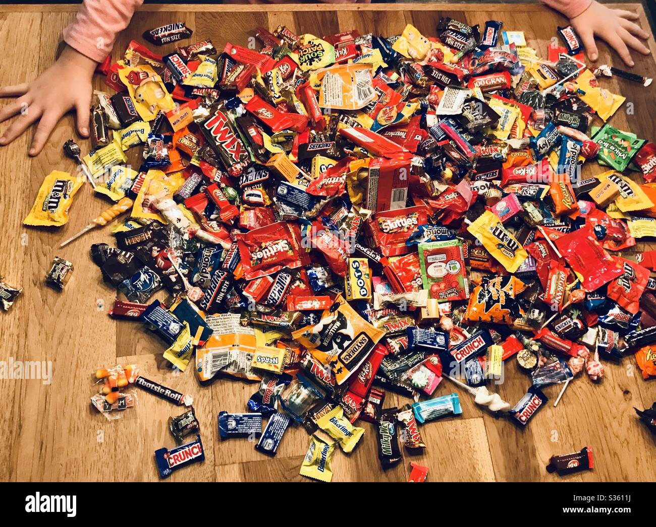 A kid looks over a huge pile of candy on a table. Stock Photo