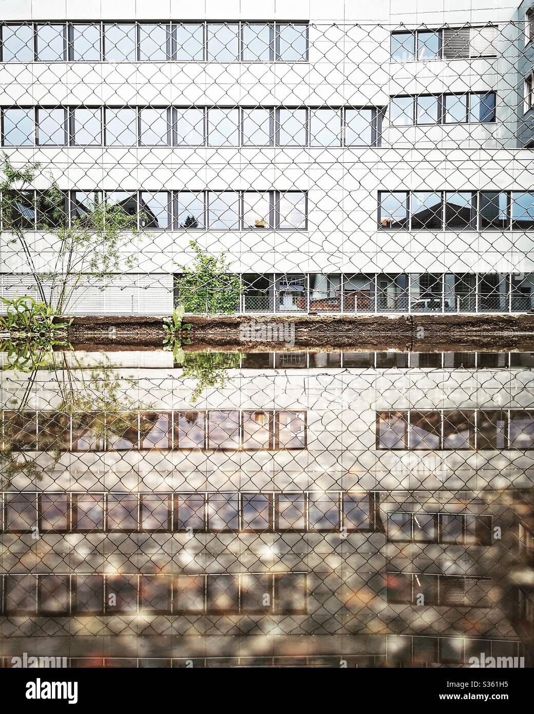 Modern office building reflected in puddle - Smartphone Captured Stock Image