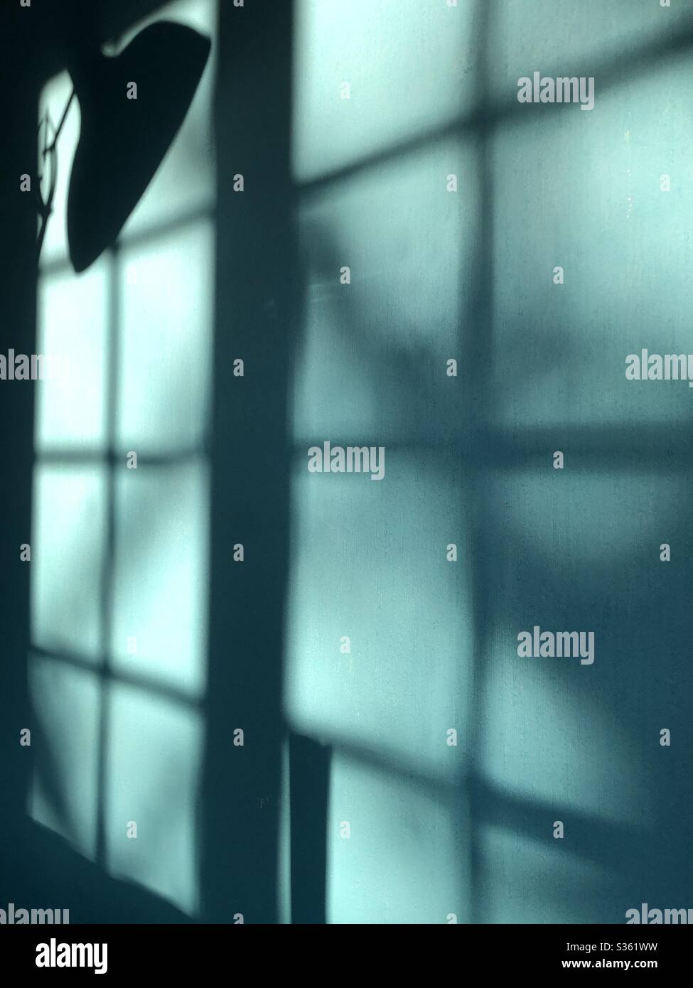 Sunlight and shadows forming multiple shapes and patterns on a blue green teal coloured wall - Smartphone Captured Stock Image