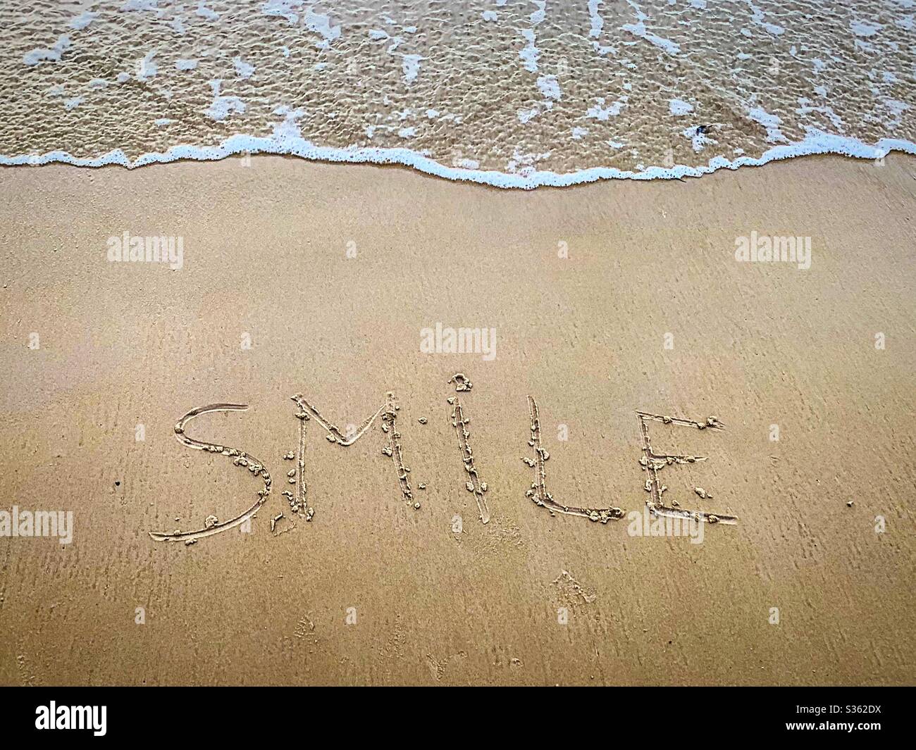 Smile written on sand at The Beach Stock Photo