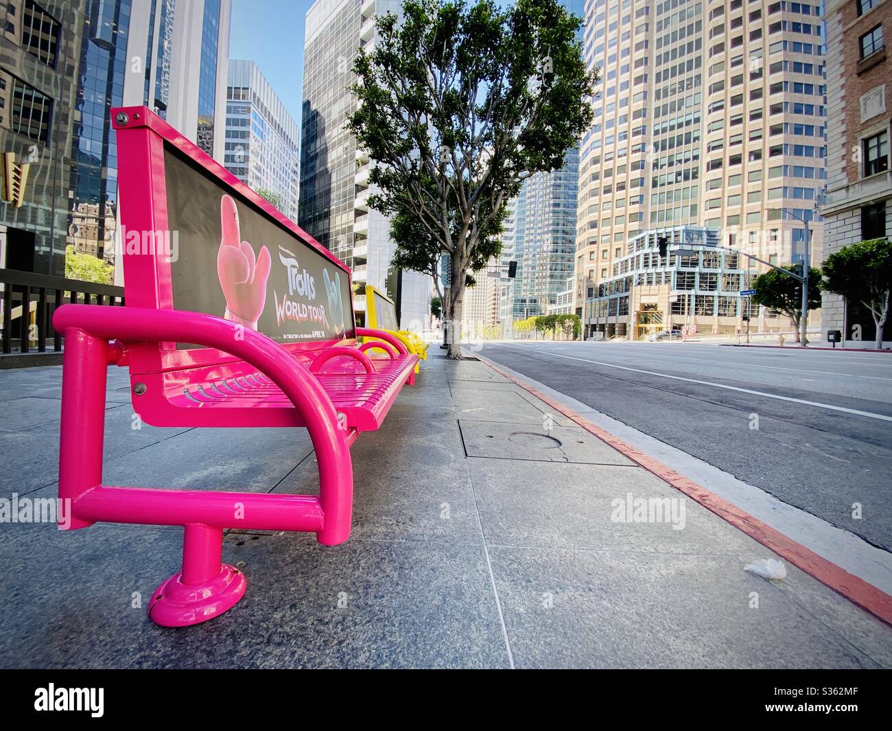 LOS ANGELES, CA, APR 2020: bright pink and yellow metal bench seats on Figueroa St in Downtown, with offices and apartments in background - Smartphone Captured Stock Image