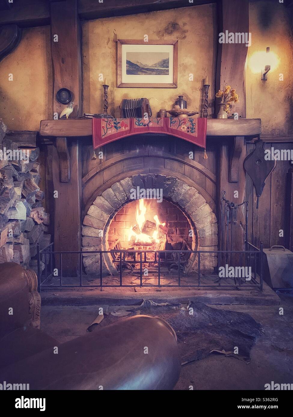 Cosy spot with a leather armchair near a fireplace in a cabin Stock Photo