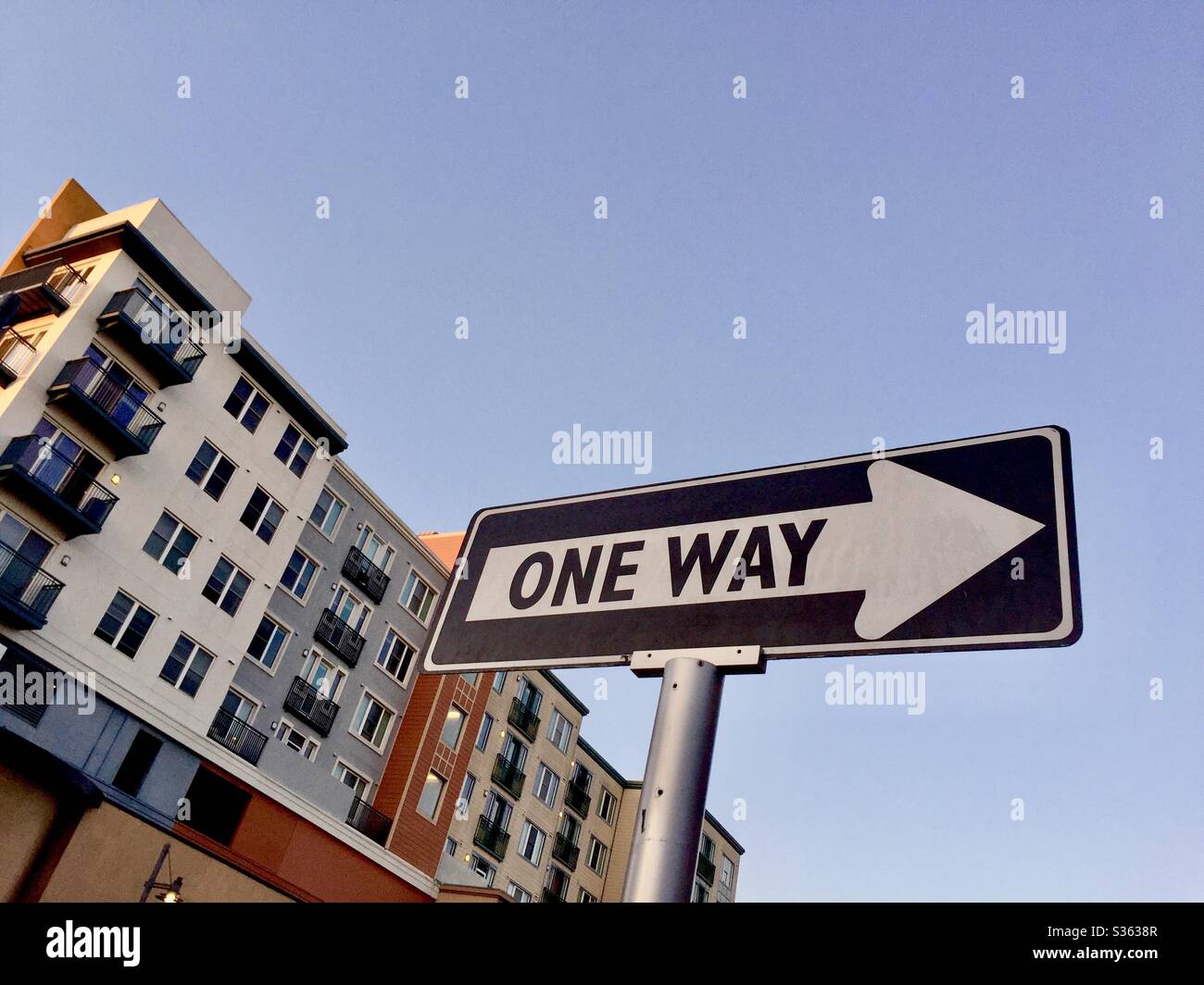 One way arrow street sign with modern pastel four-story apartments behind it. Bay Street, Emeryville, California. - Smartphone Captured Stock Image