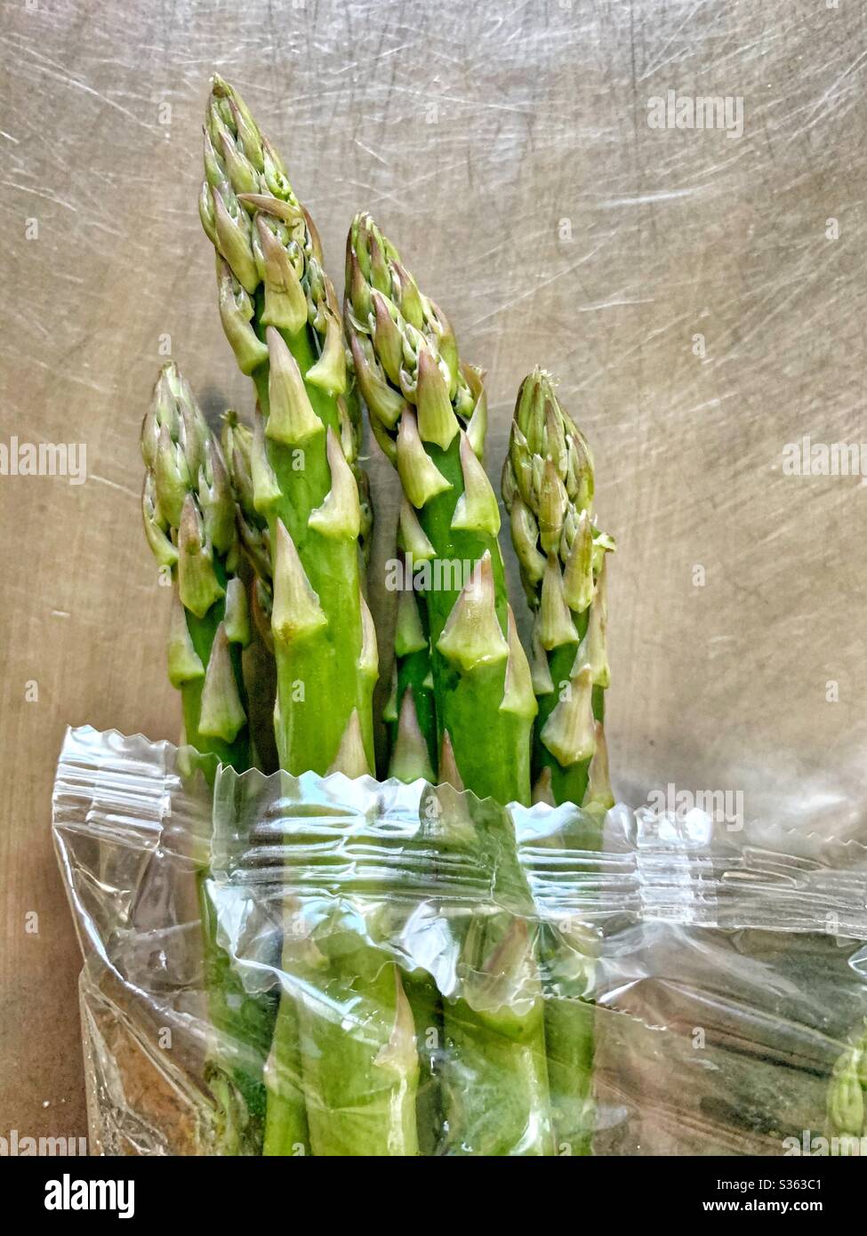 A pound of fresh Asparagus in plastic on table Stock Photo
