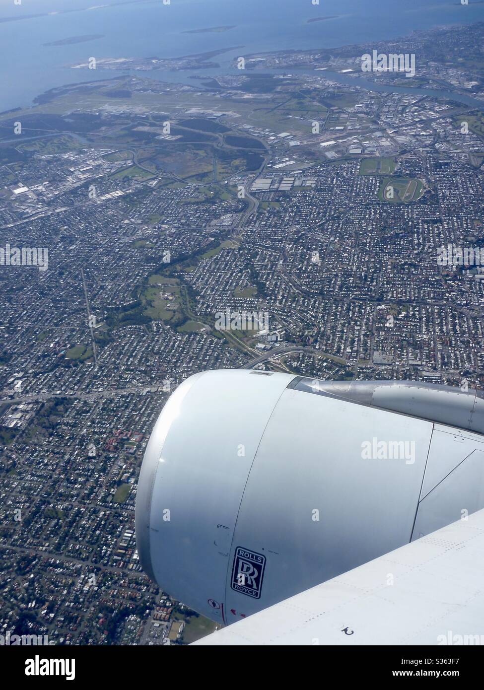 Aerial image looking over the wing and engine of Brisbane Northern Suburbs and Brisbane International Airport. Stock Photo