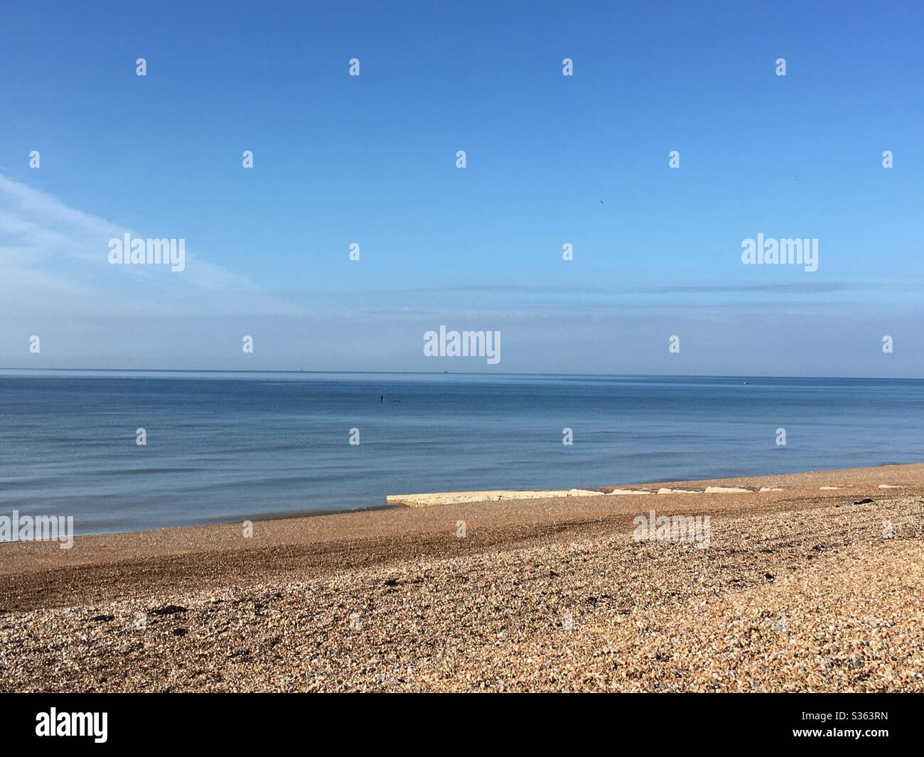 Shingle beach and calm blue sea - Smartphone Captured Stock Image