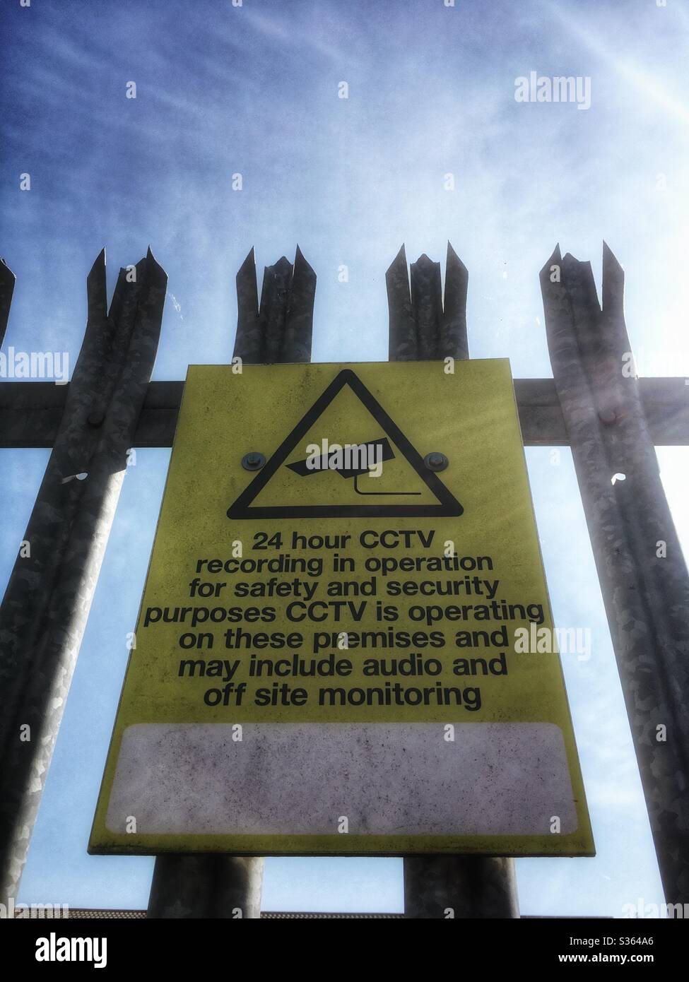 CCTV warning sign on spiked fence Stock Photo