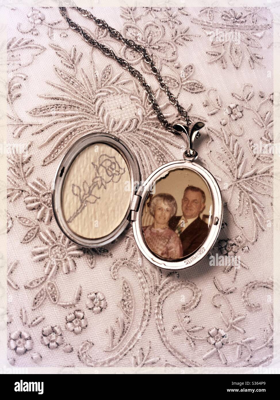 Vintage Silver photo locket on embroidered lace background,  USA 1971 - Smartphone Captured Stock Image