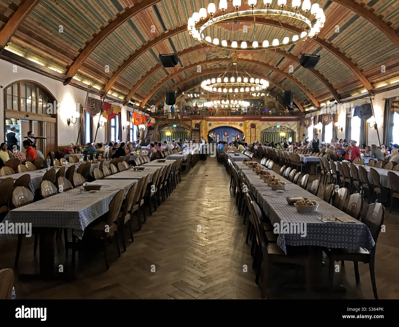 Munich, Germany - June 23, 2017: The Hofbrauhaus Munchen festival hall interior is shown, with patrons dining and a band playing at the back of the room. - Smartphone Captured Stock Image
