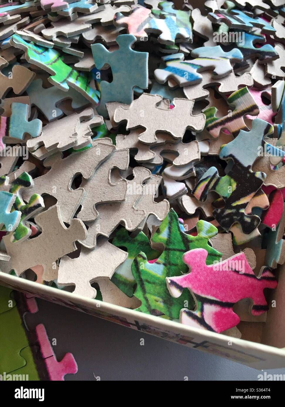 Jigsaw puzzle pieces in a cardboard box - Smartphone Captured Stock Image