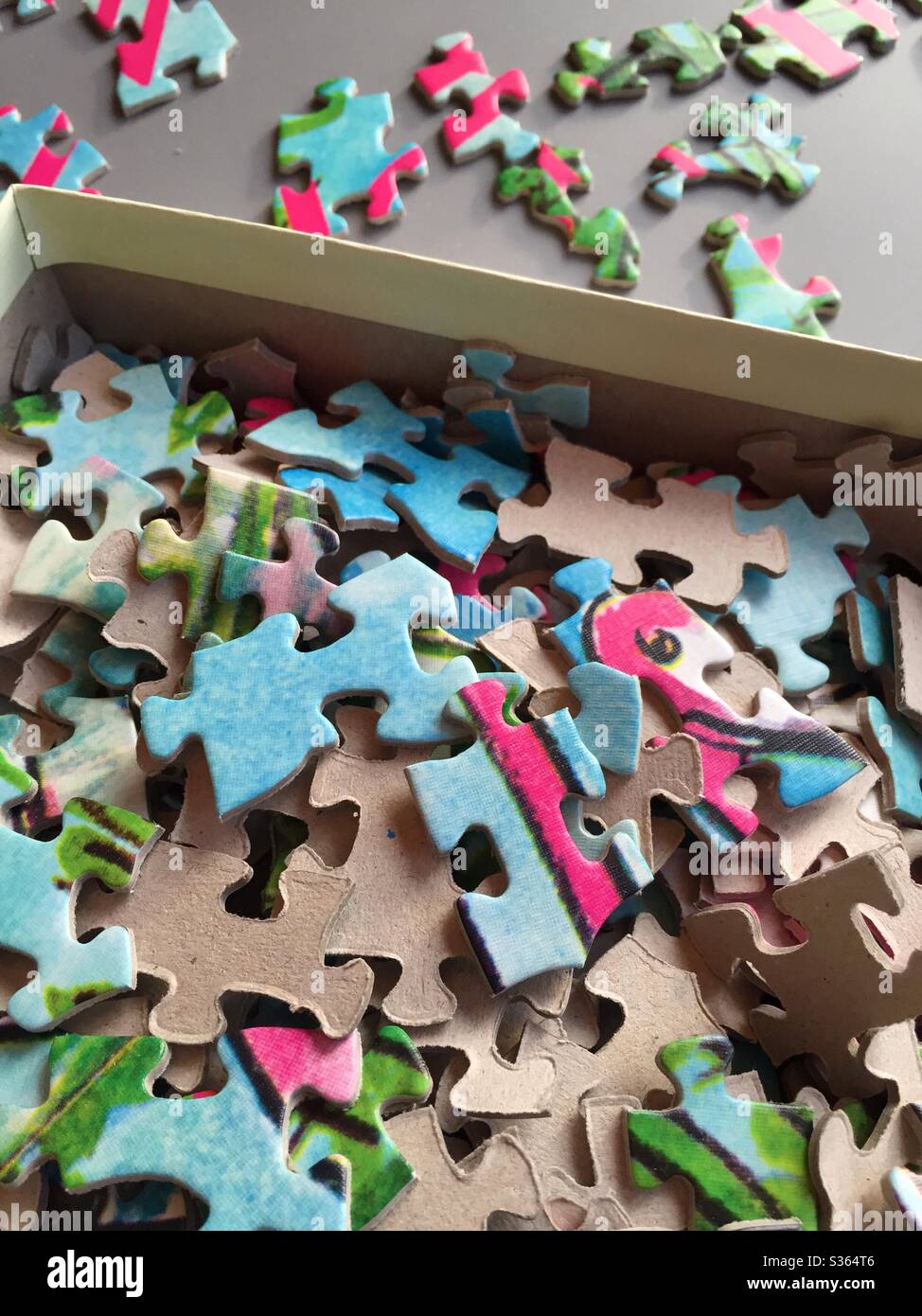 Jigsaw puzzle pieces unassembled in a box and on an assembly board