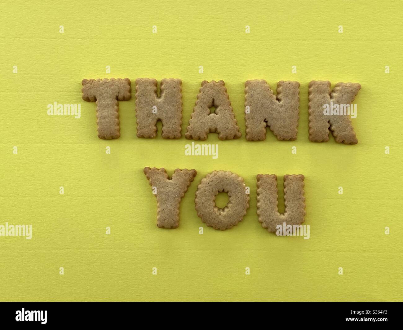Thank you text composed with biscuit letters over yellow backround - Smartphone Captured Stock Image