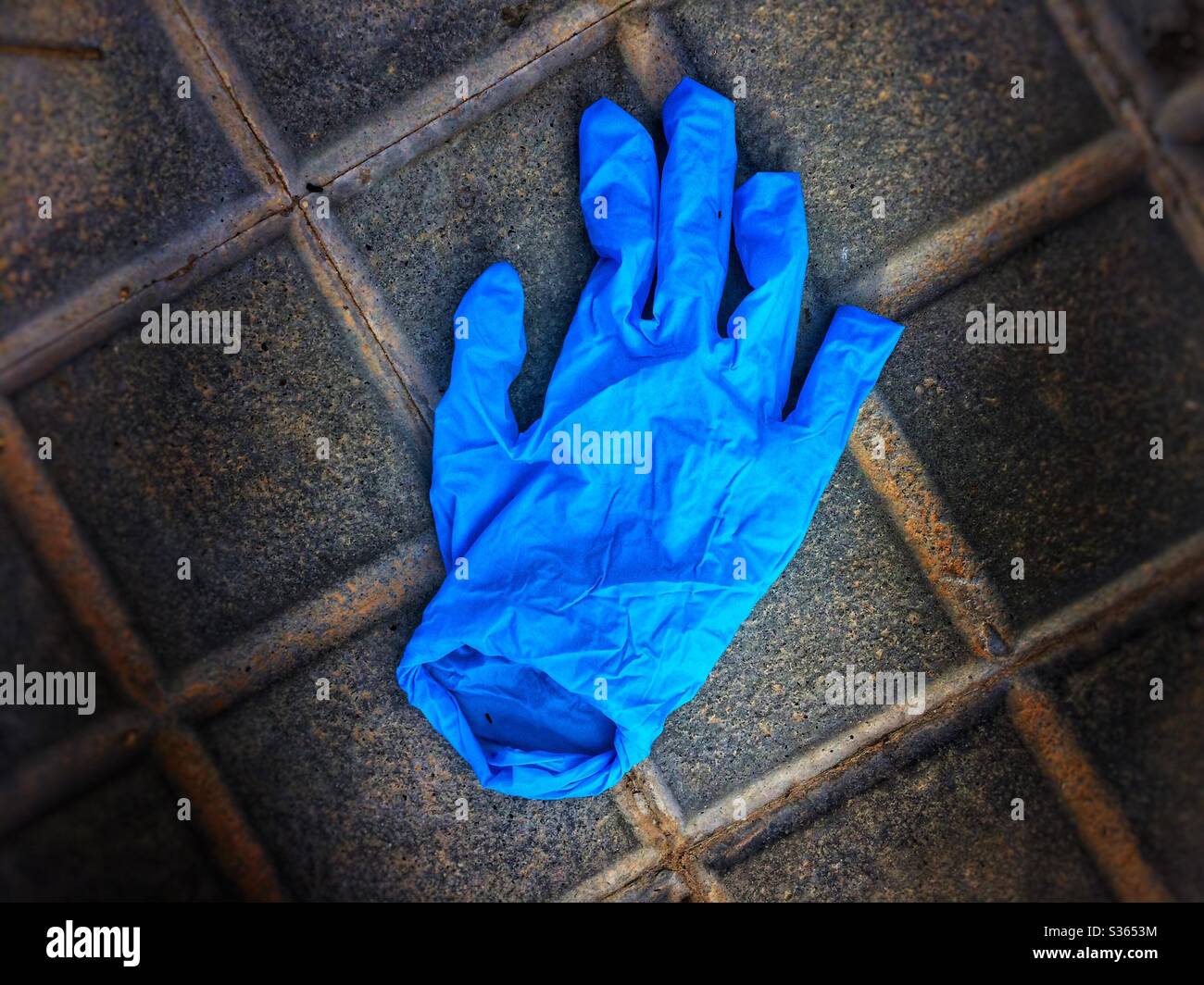 Abandoned blue protective latex glove avandoned on the street Stock Photo