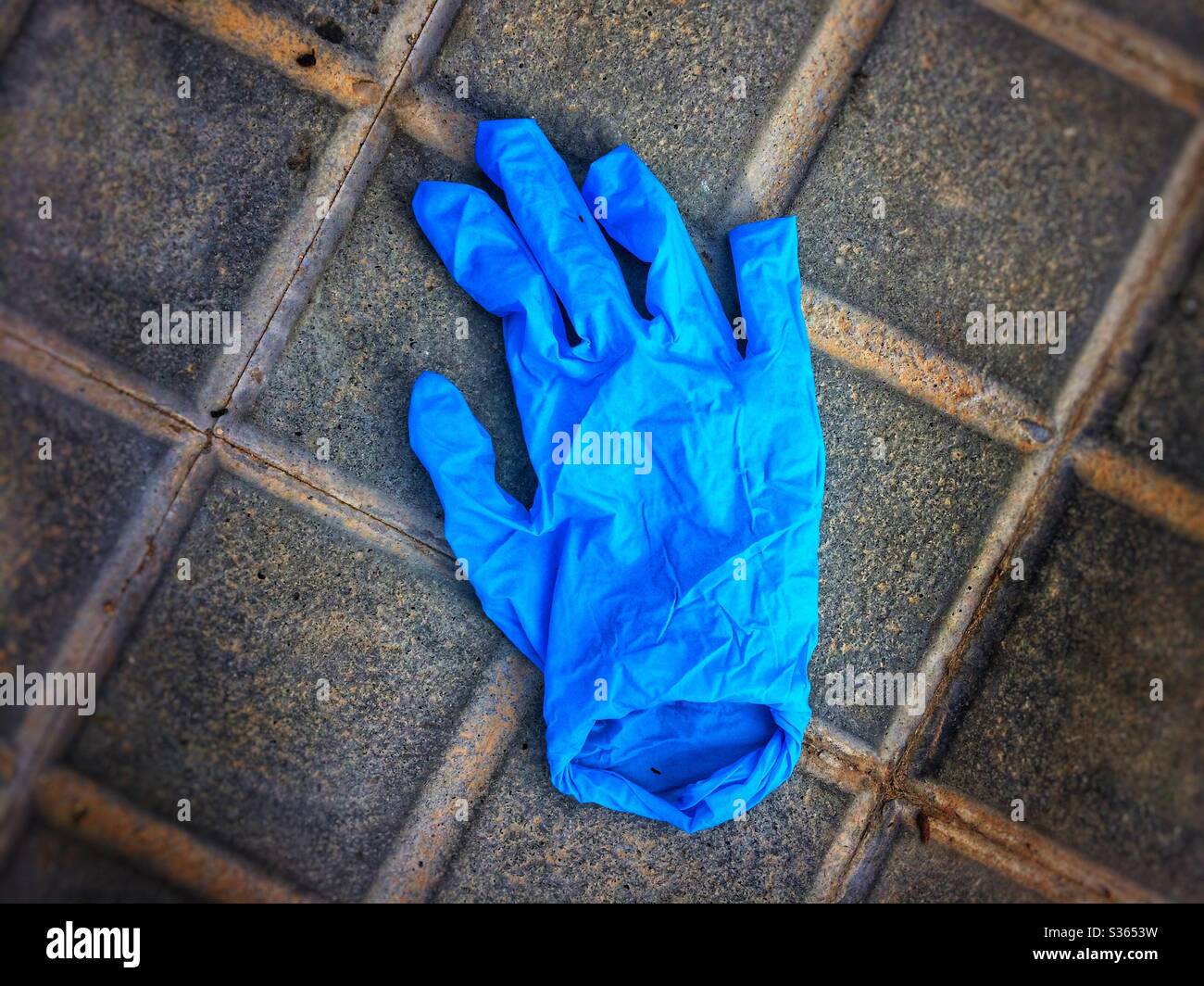 Protective blue latex glove abandoned on the floor Stock Photo