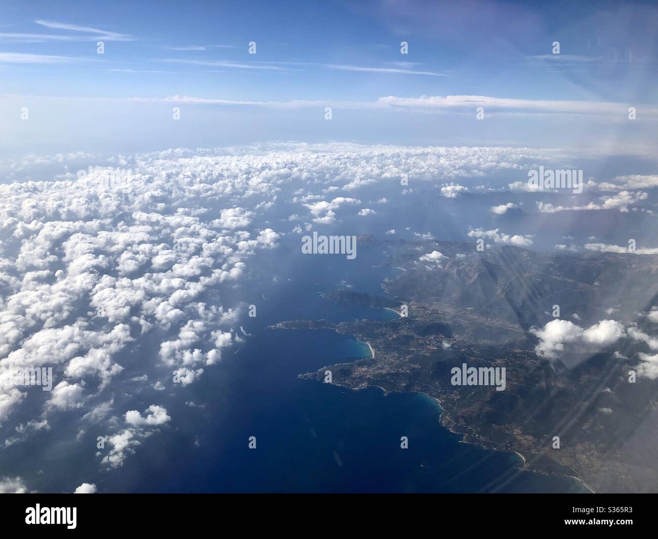 View from the air of Corsica island coast line - clouds in a sunny day and view of the blue water of the Mediterranean sea - Smartphone Captured Stock Image
