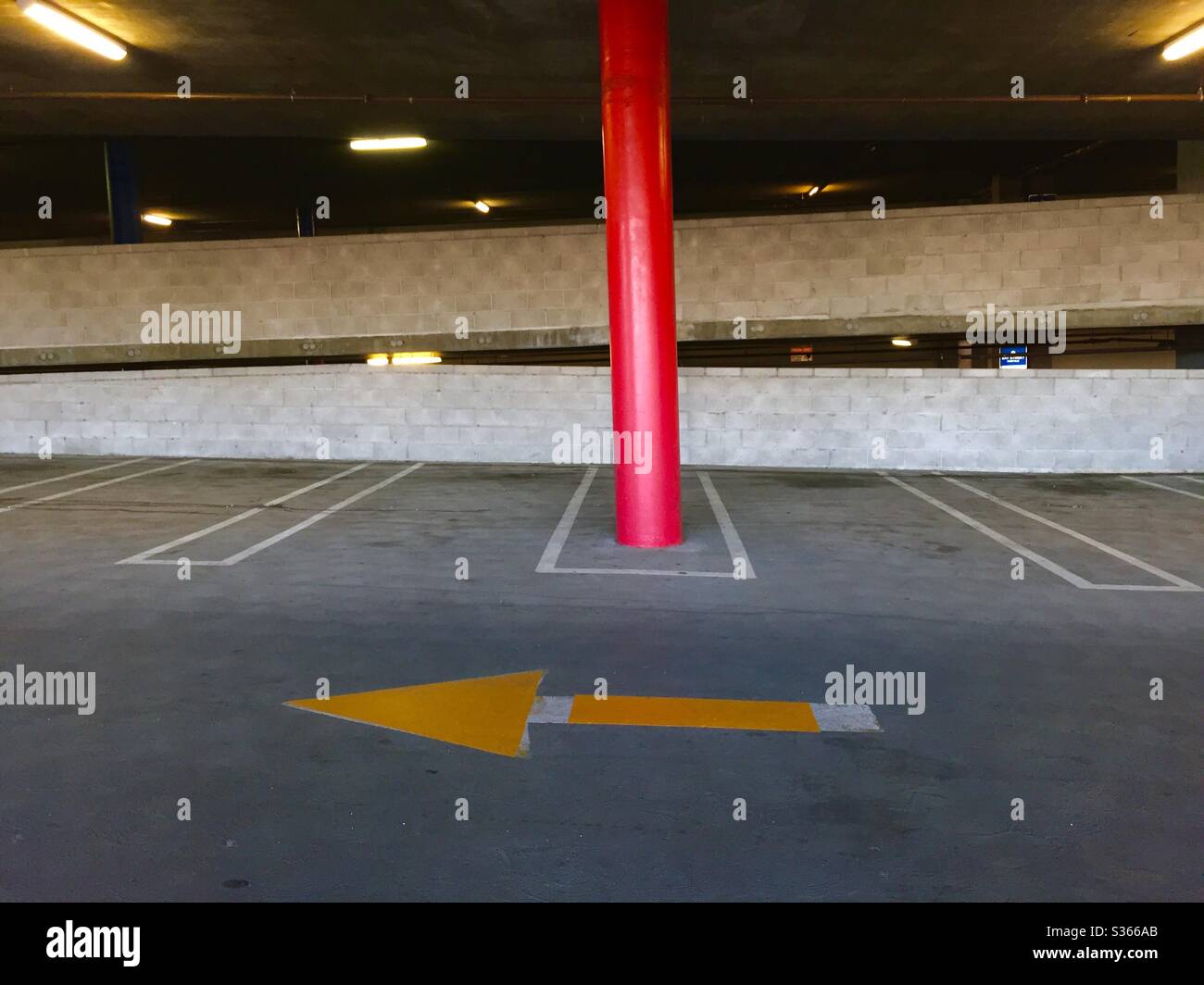 Red pillar and yellow arrown in a multi-level parking garage. Stock Photo