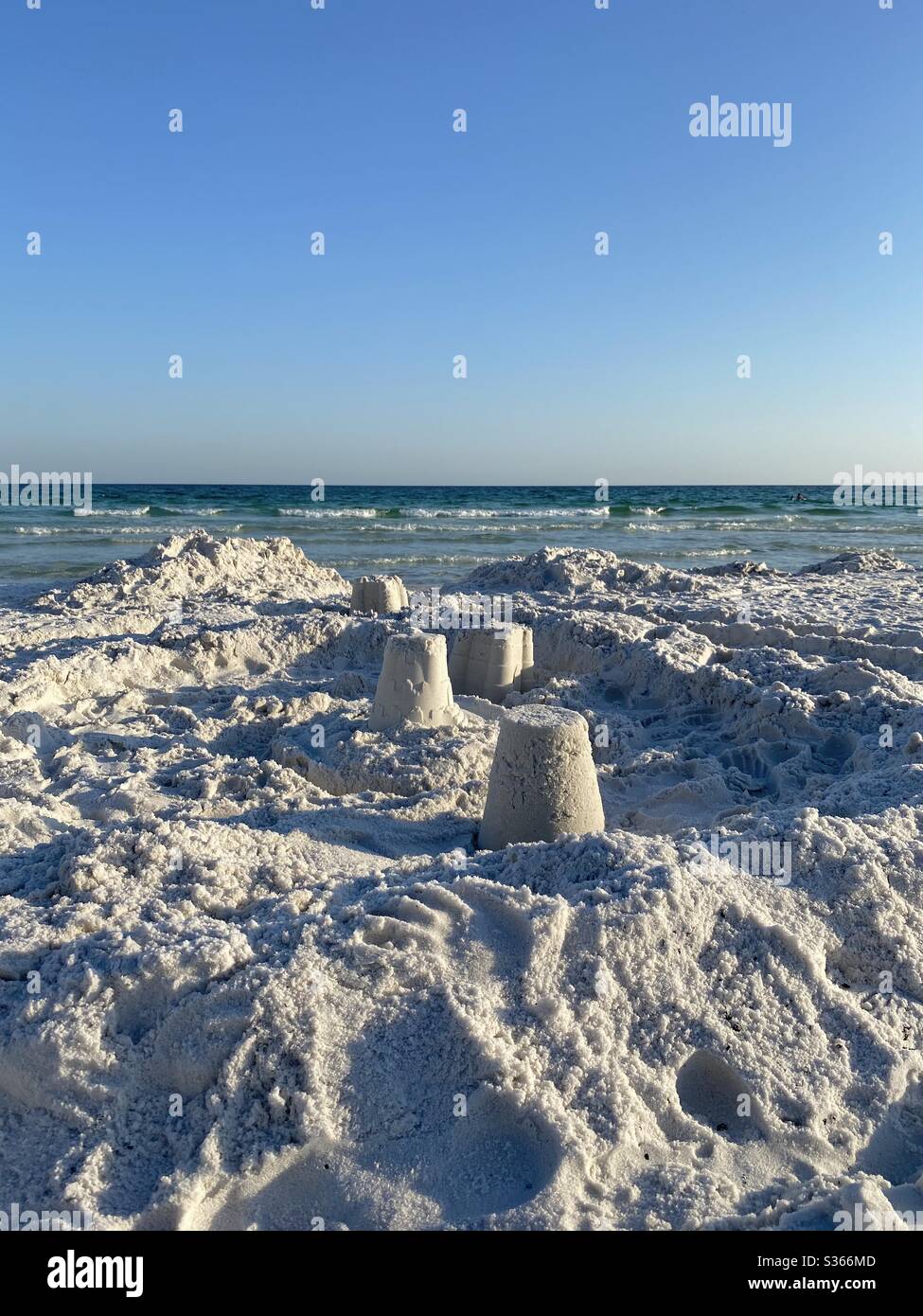 Sandcastles on white sand beach with view of emerald water of the Gulf of Mexico - Smartphone Captured Stock Image