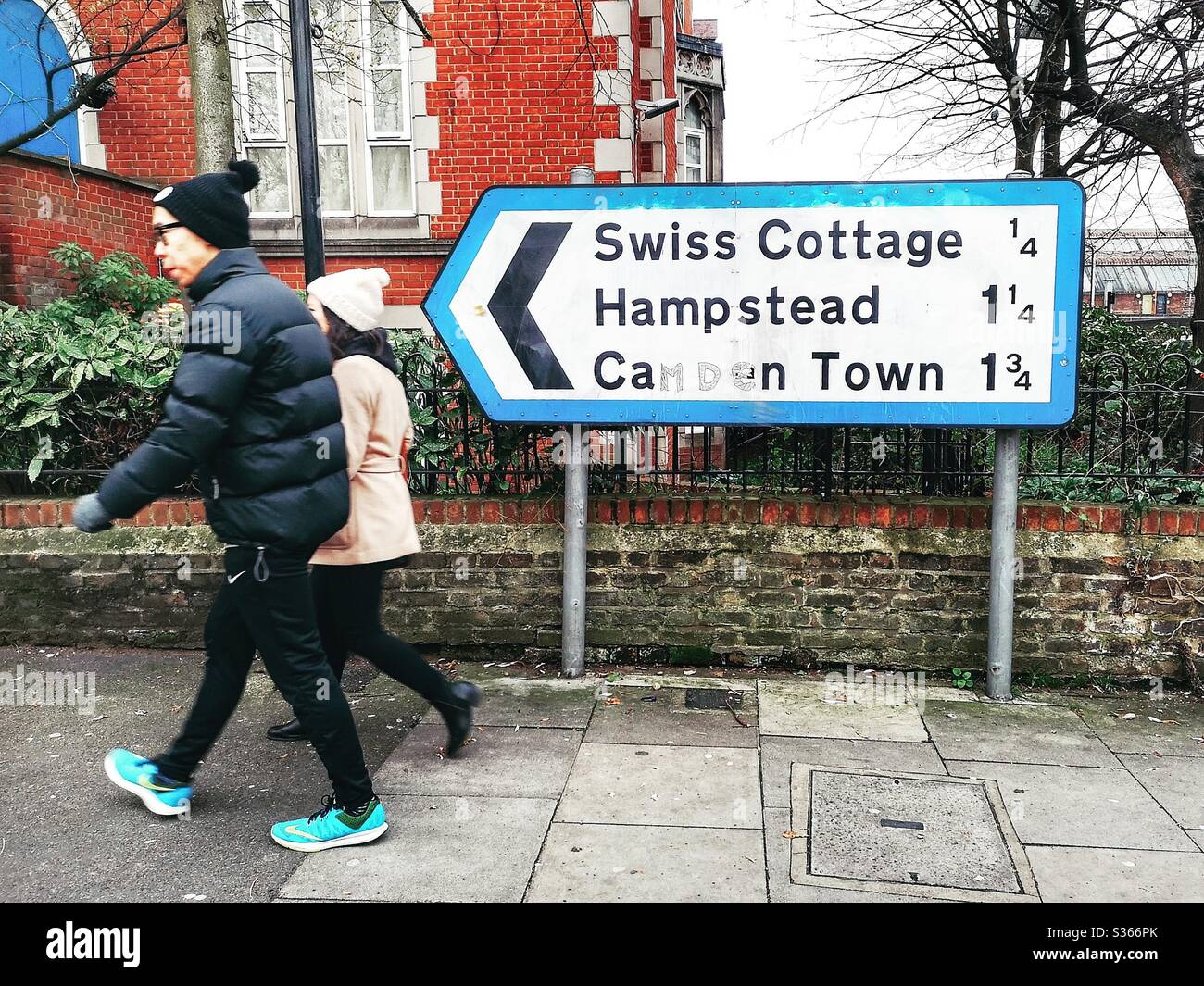 Couple walk past road sign, London - Smartphone Captured Stock Image