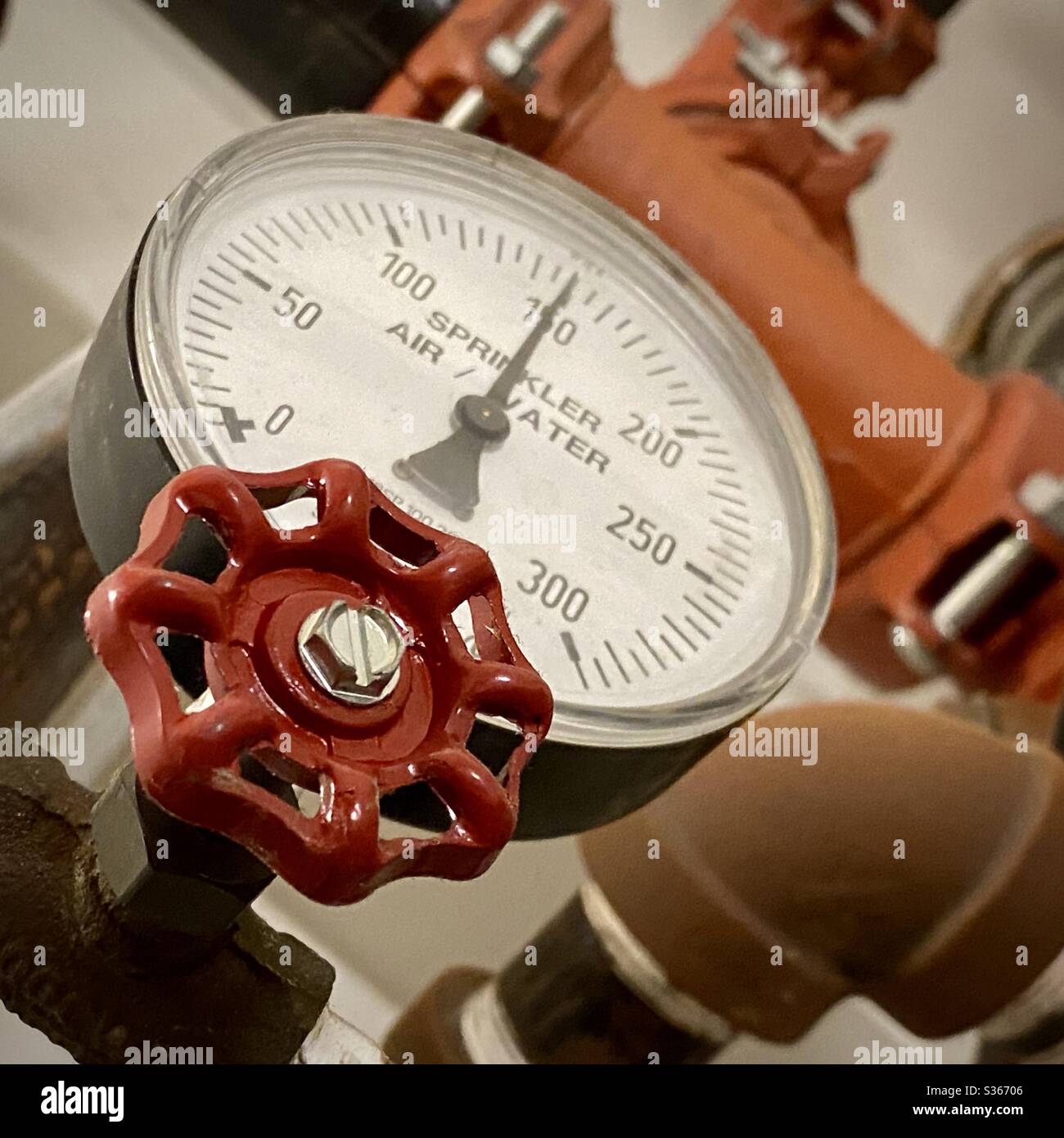 Angled view of red, sprinkler system tap and pressure gauge, part of fire-fighting system in apartment building - Smartphone Captured Stock Image