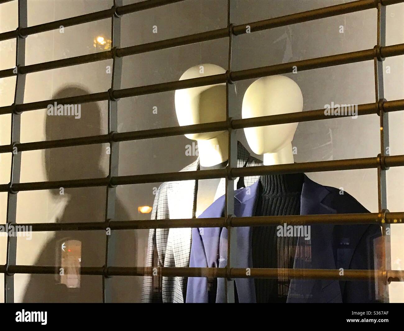 Two mannequins in the shop window of a closed shop. - Smartphone Captured Stock Image