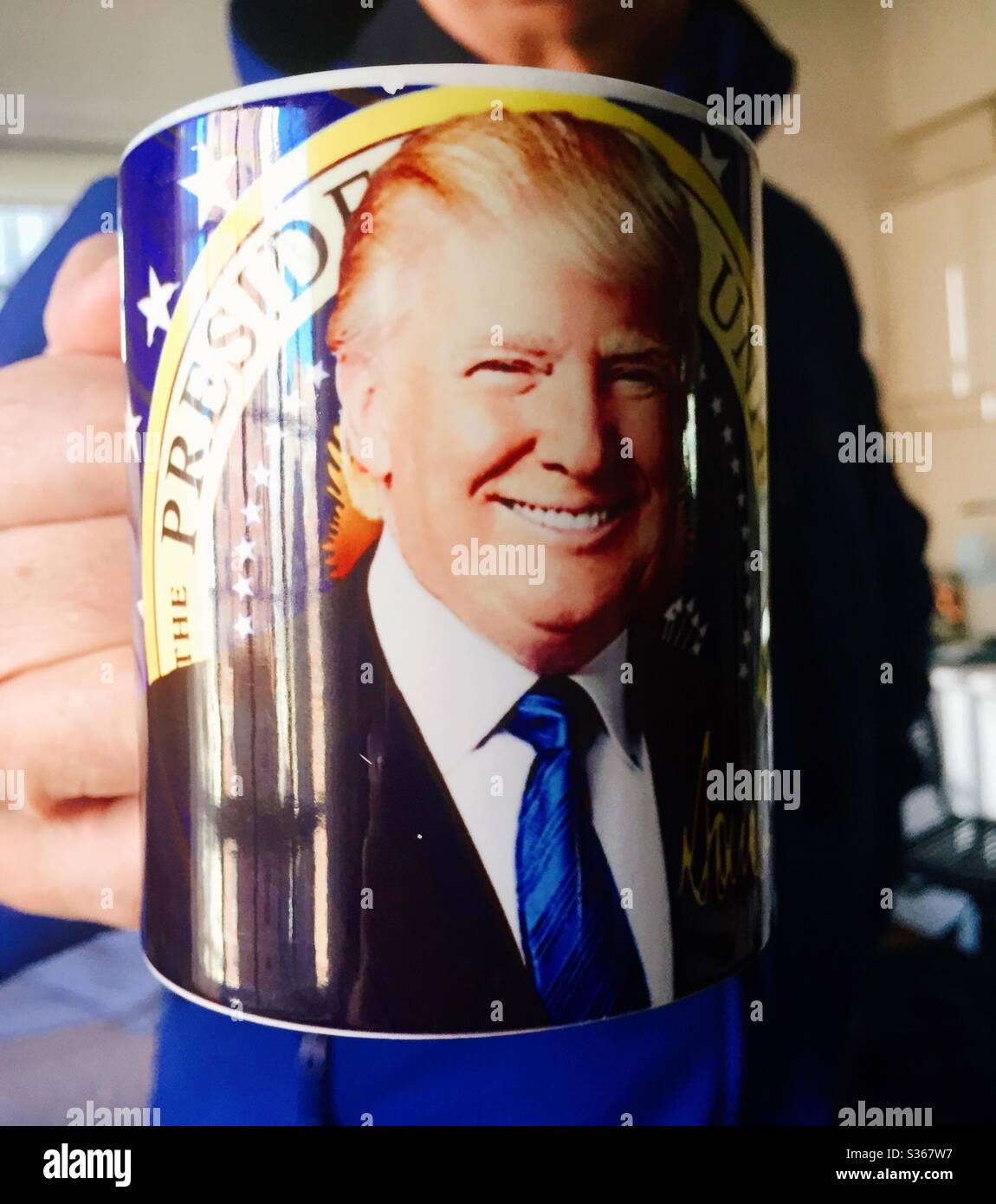 Coffee mug with President Donald Trump‘s picture on it being proudly held by a proud American. - Smartphone Captured Stock Image