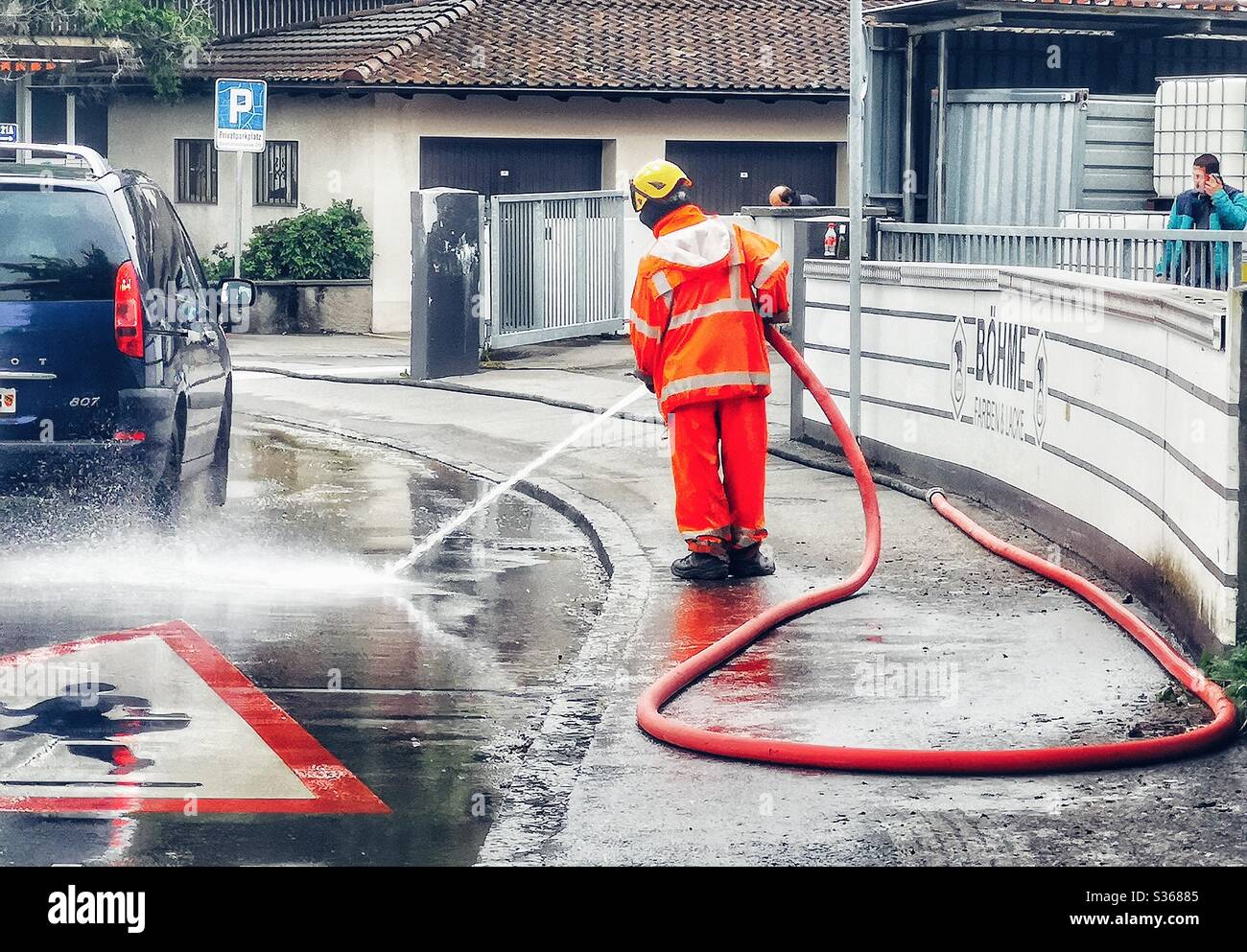 Man in hazmat suit hosing down street - Smartphone Captured Stock Image