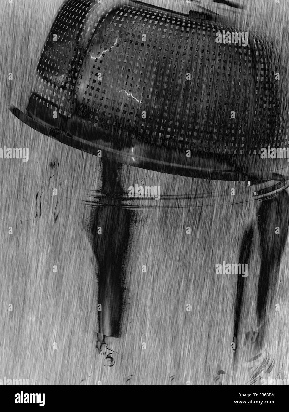 The imaginary scene of the upside down drain plastic food bucket and the metallic soup cooking ware beyond the thunder lights and the big rain in black and white Stock Photo