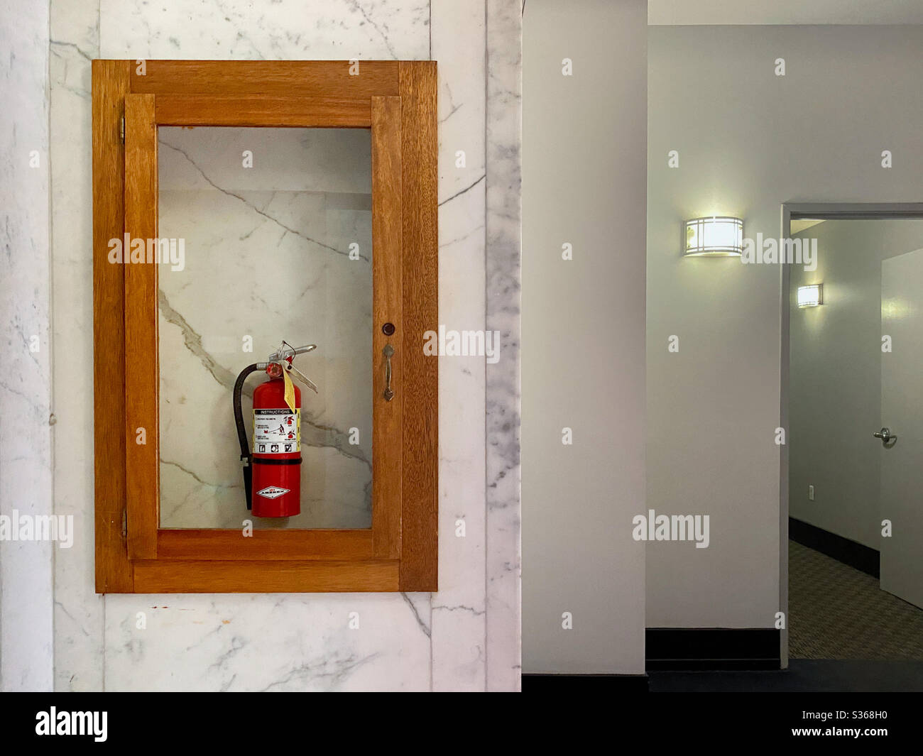 LOS ANGELES, CA, APR 2020 fire extinguisher in glass on marble wall, inside a Downtown