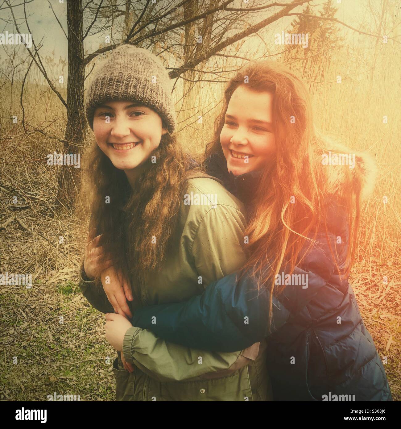 Two teenage girls embracing and smiling outdoors Stock Photo