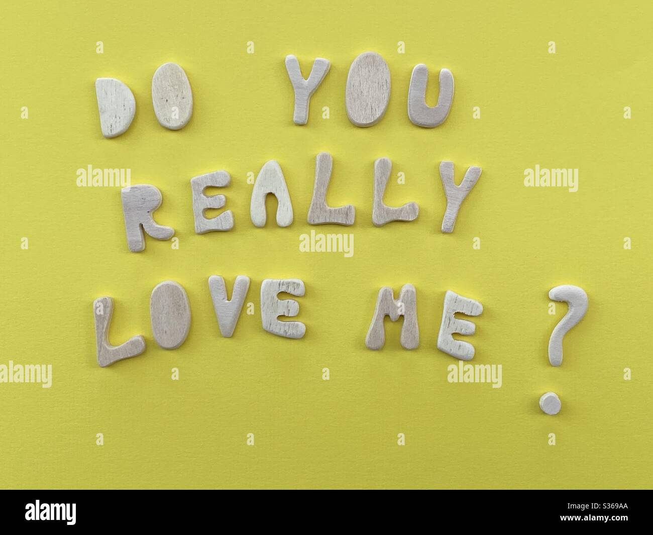 Do you really love me ? Typical question composed with wooden letters over yellow color Stock Photo
