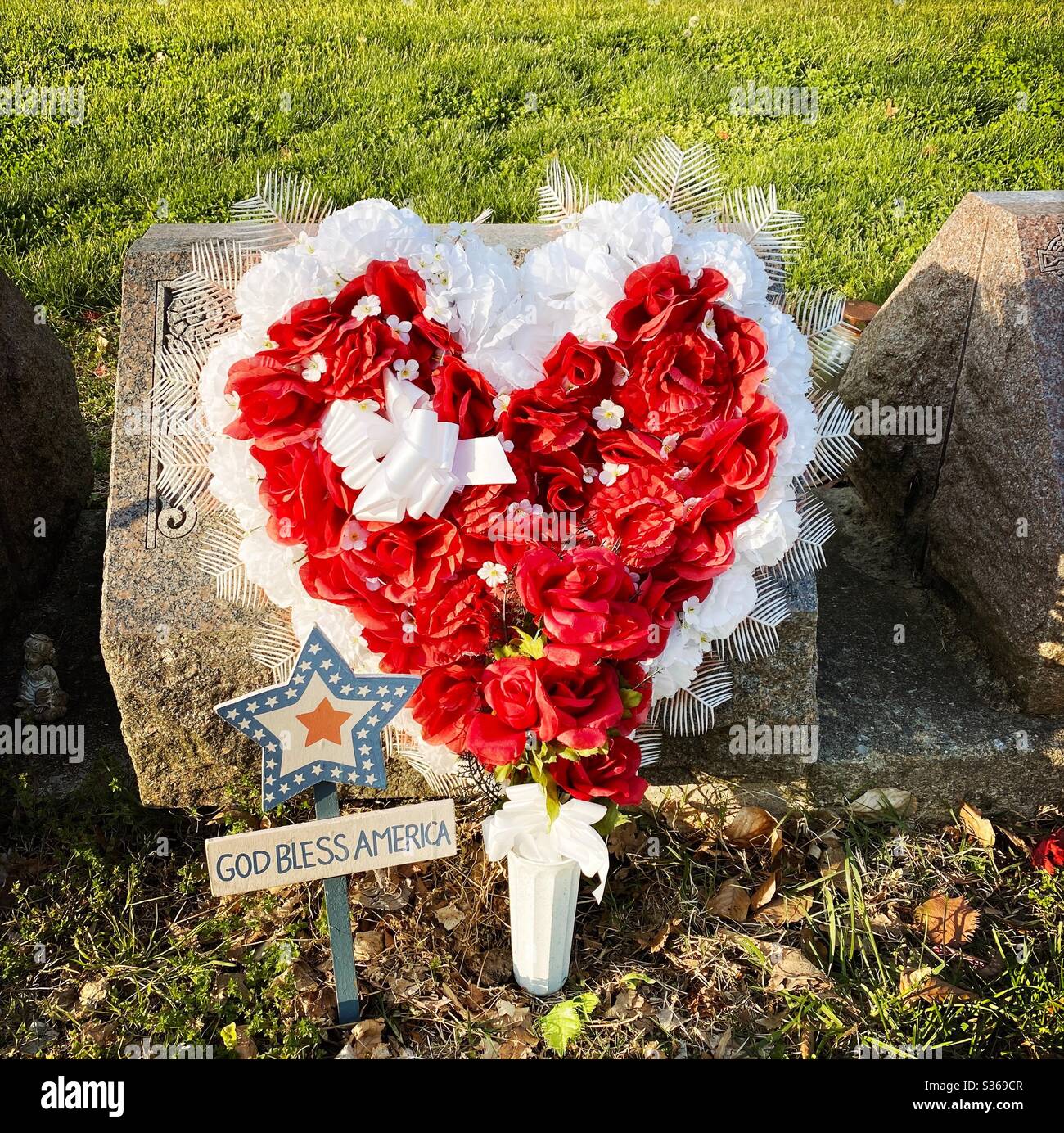 Flowers left at a gravestone with sign that says God Bless America - Smartphone Captured Stock Image