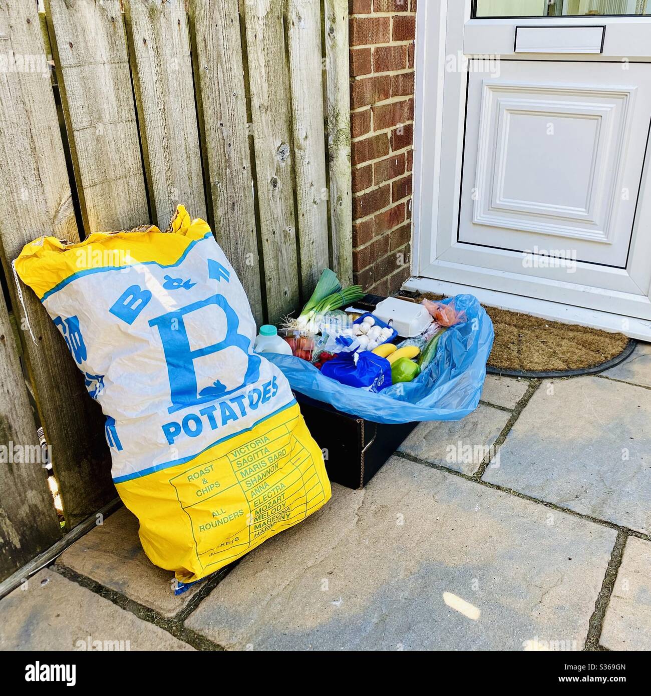 Contactless doorstep delivery of fresh farm goods during the coronavirus lockdown. Fresh vegetables, eggs and potatoes delivered to the door by a local grocer - Smartphone Captured Stock Image
