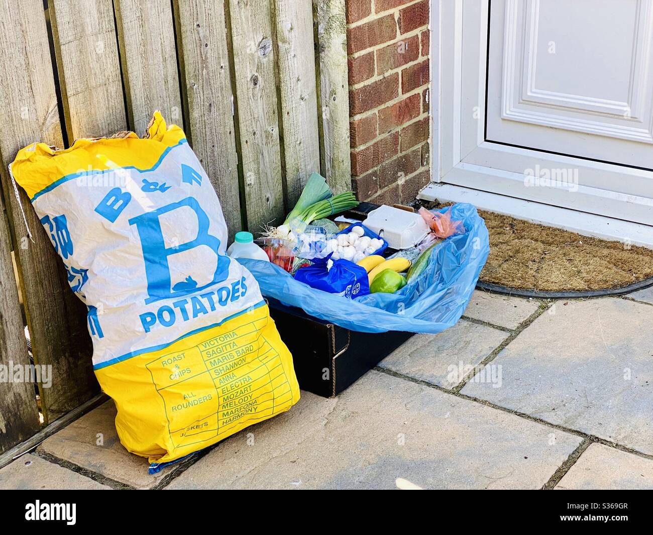 Contactless doorstep delivery of fresh farm goods during the coronavirus lockdown. Fresh vegetables, eggs and potatoes delivered to the door by a local grocer - Smartphone Captured Stock Image