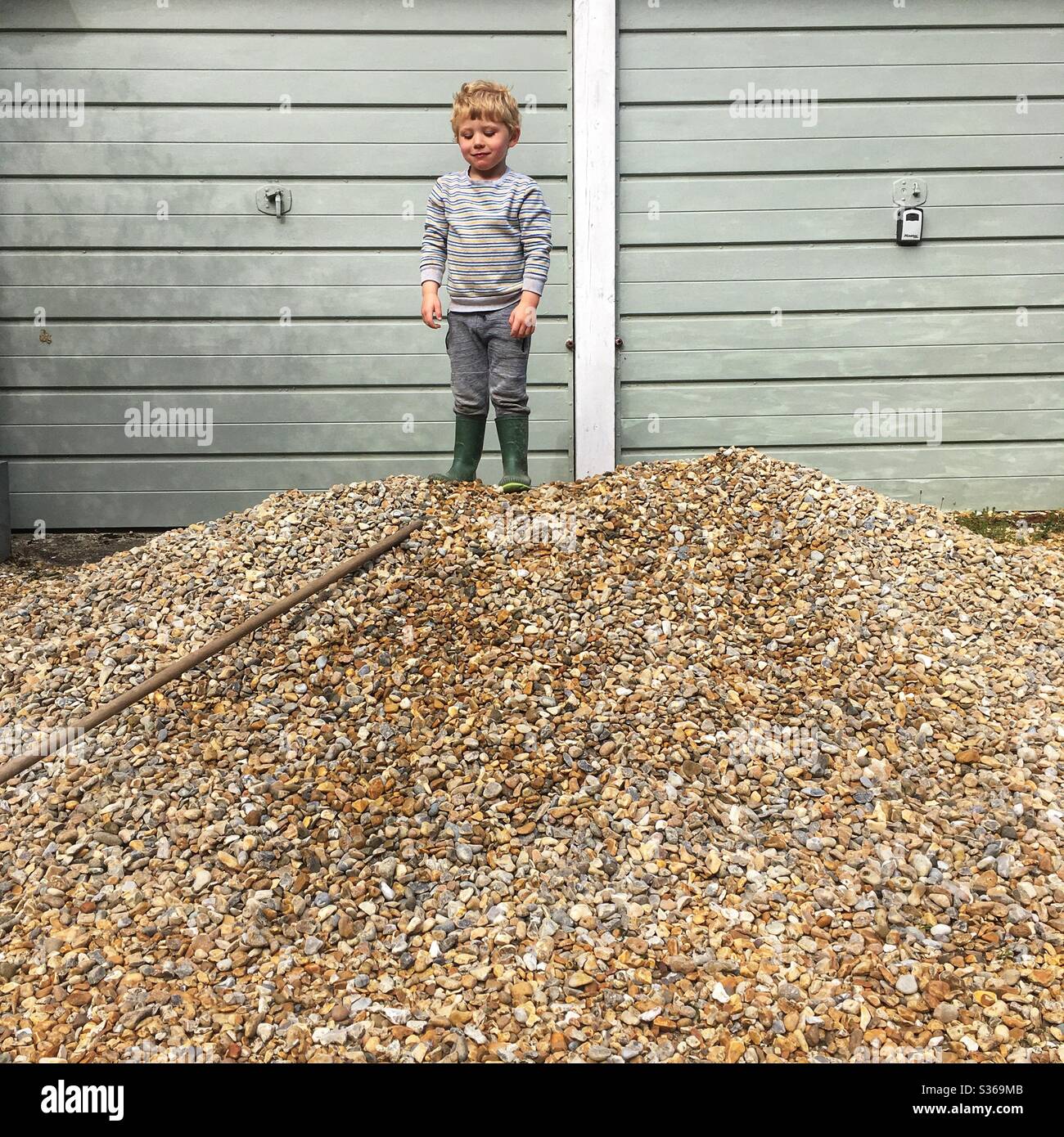 Three year old boy standing on a pile of gravel Stock Photo - Alamy
