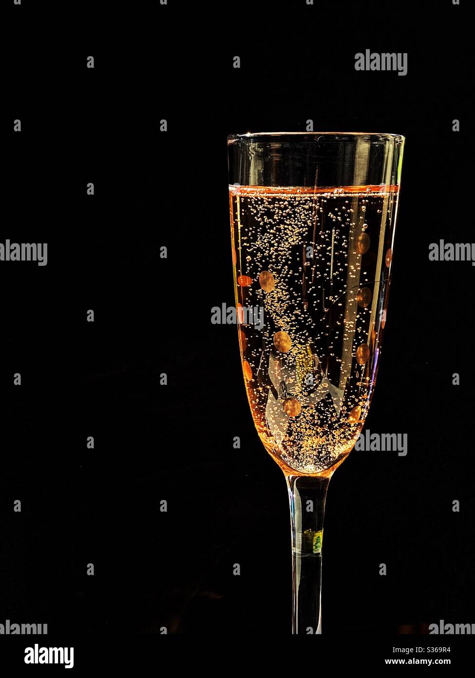 Glass of pink champagne against a black background. Space for copy. No people. - Smartphone Captured Stock Image