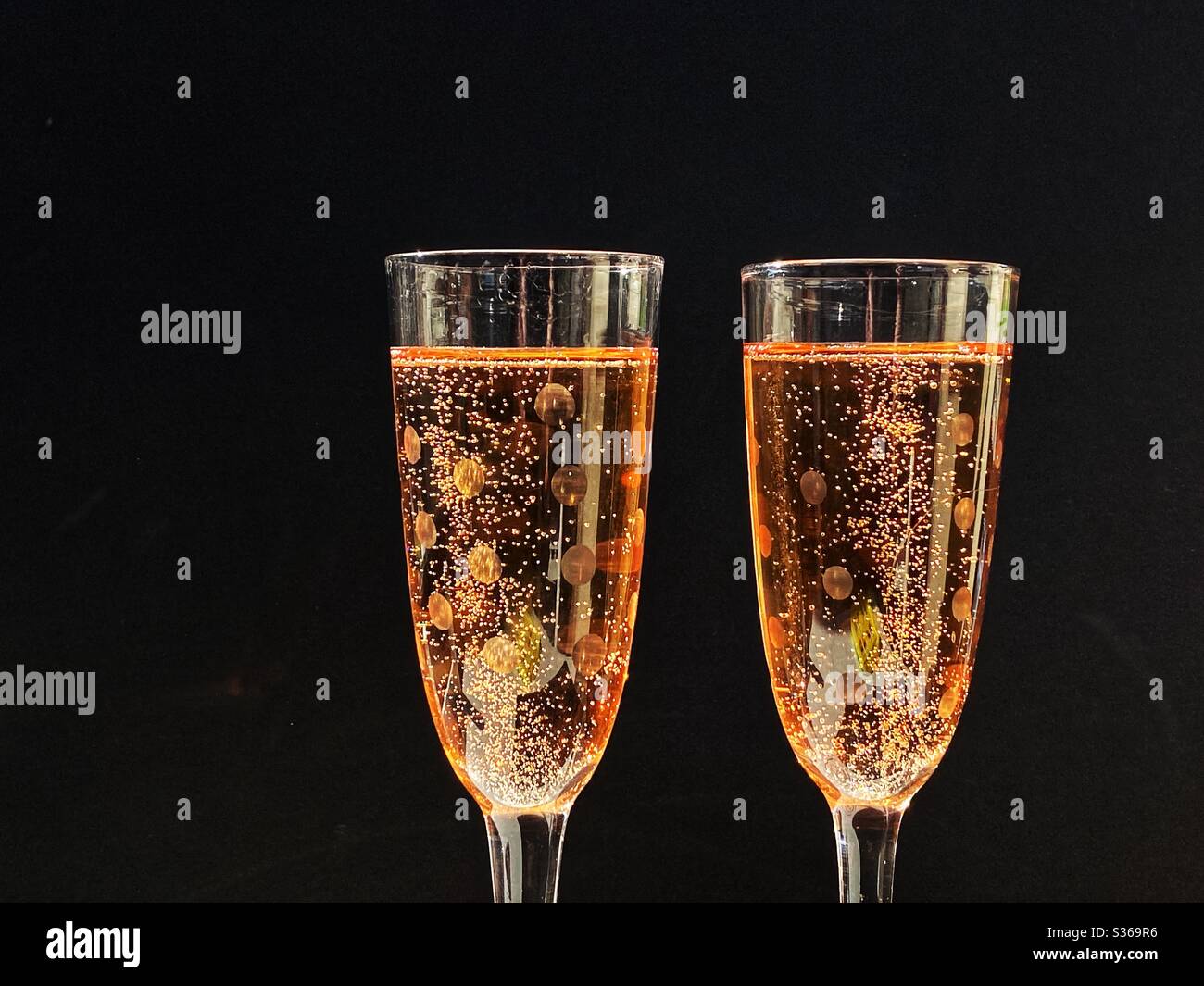 Pair of glasses full of pink champagne against a black background. No people. Space for copy. Stock Photo