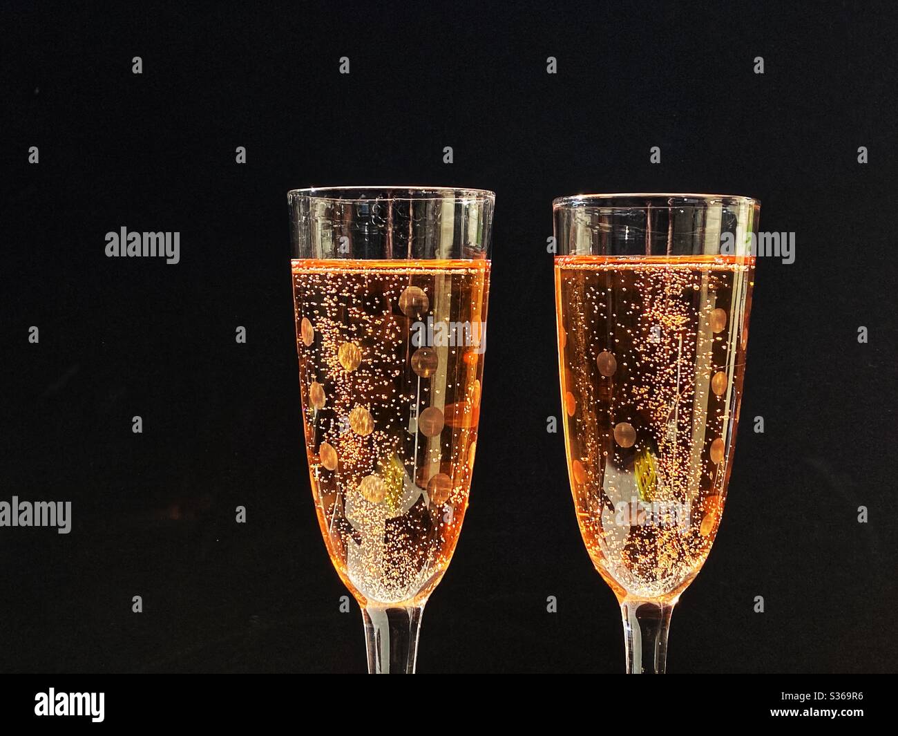 Pair of glasses full of pink champagne against a black background. No people. Space for copy. - Smartphone Captured Stock Image