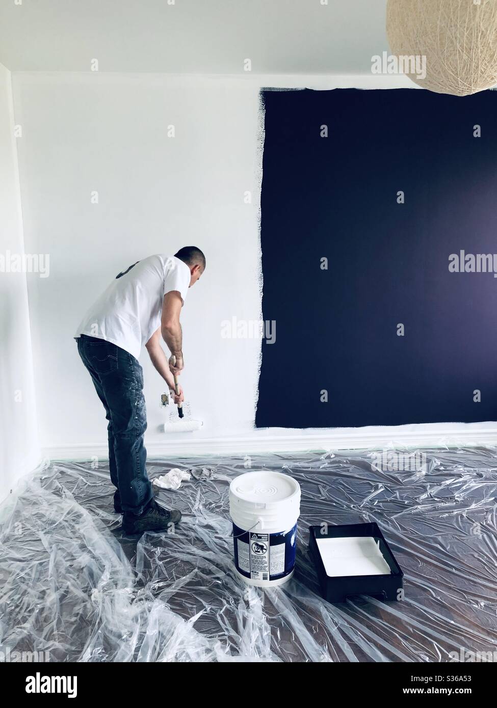 Man painting walls in a room from purple to white - Smartphone Captured Stock Image