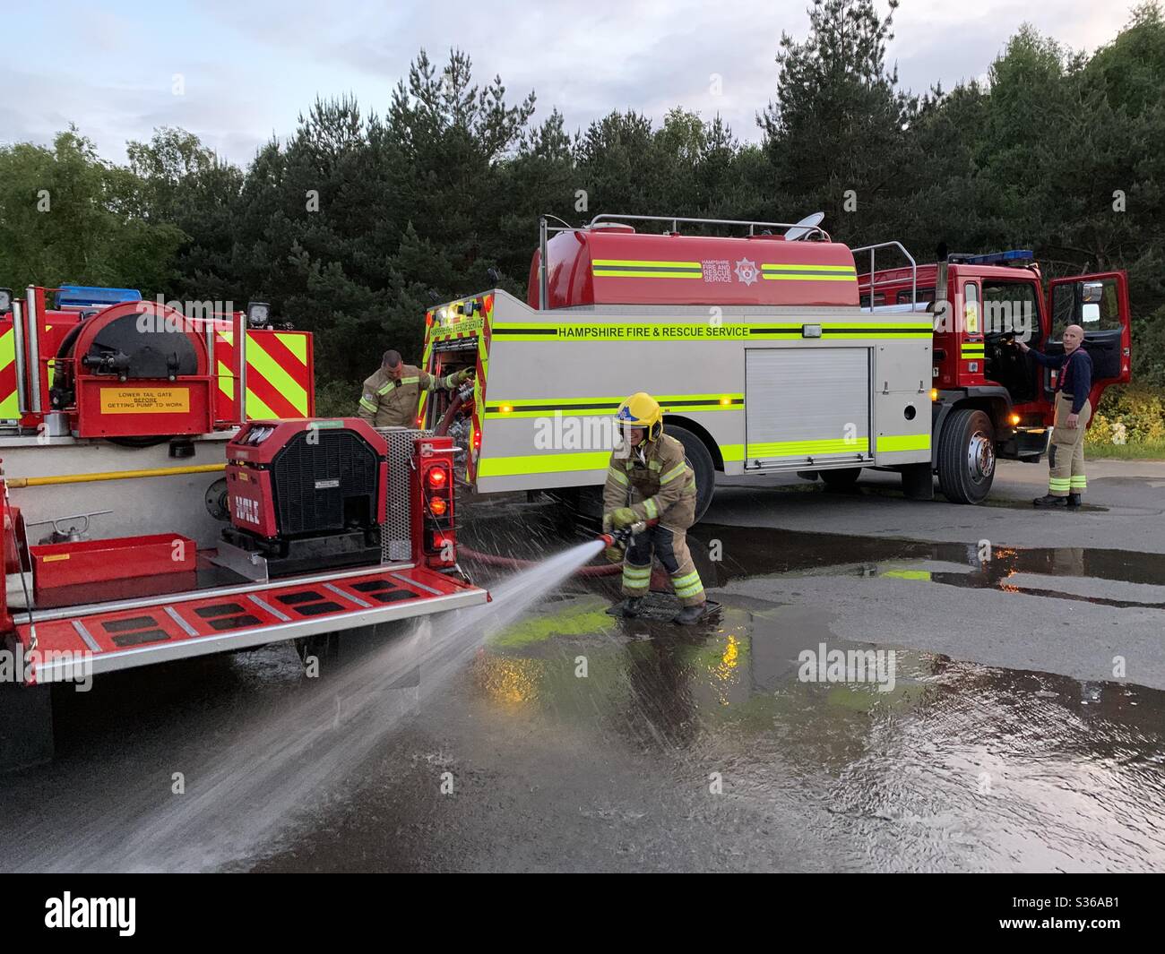 A firefighter sprays water from a water carrier tanker truck to clean
