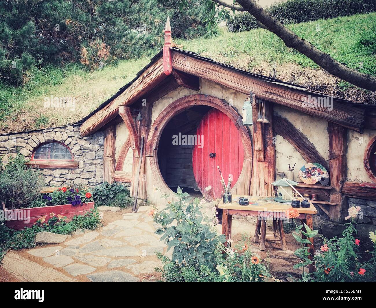Hobbiton. Bucolic place in New Zealand where the hobbits from the Middle Earth live. Lord of the rings movie set. Red wooden round door Stock Photo